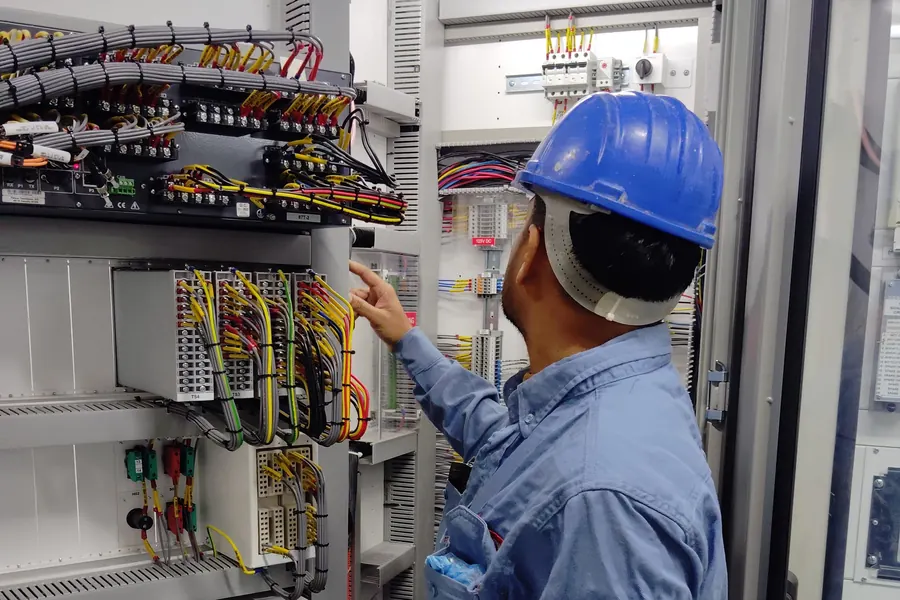 Ticari bir tesiste dağıtım panosu üzerinde çalışan elektrik teknisyeni